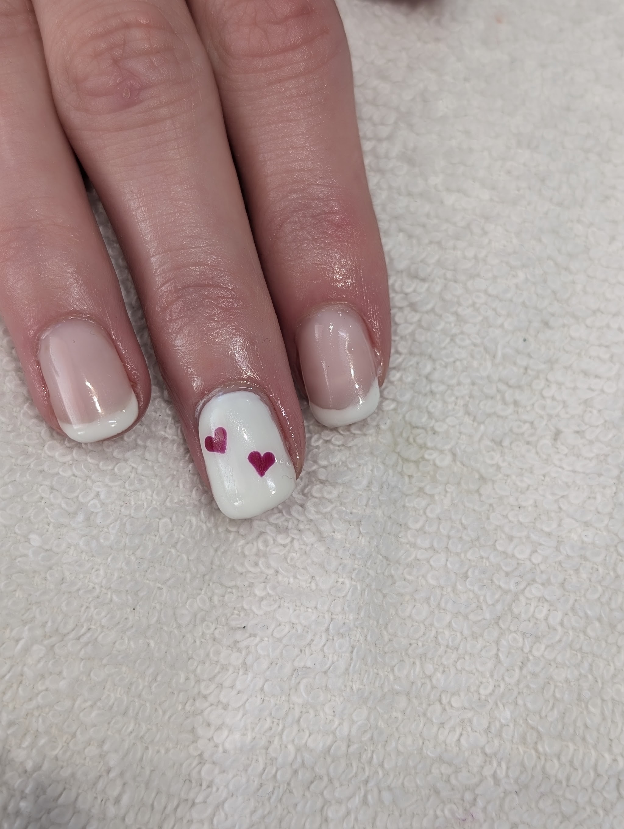 French manicure with a white accent nail and two red hearts